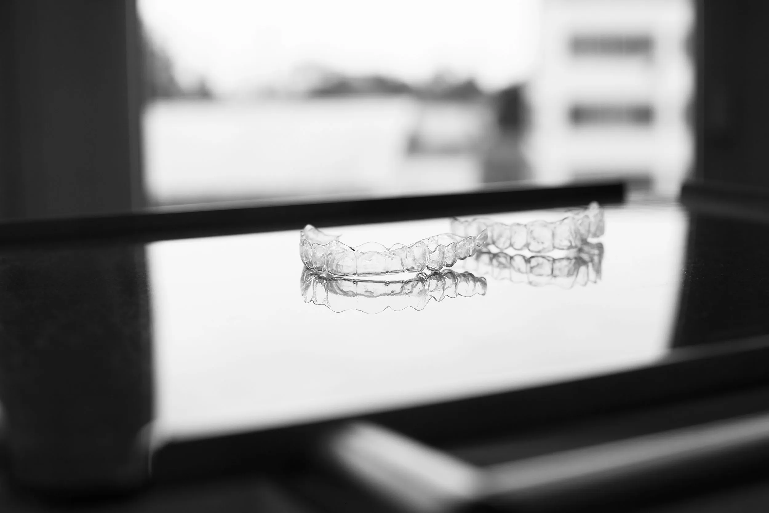 Zwei "unsichtbare" Zahnspangen liegen nebeneinander auf einem Tisch