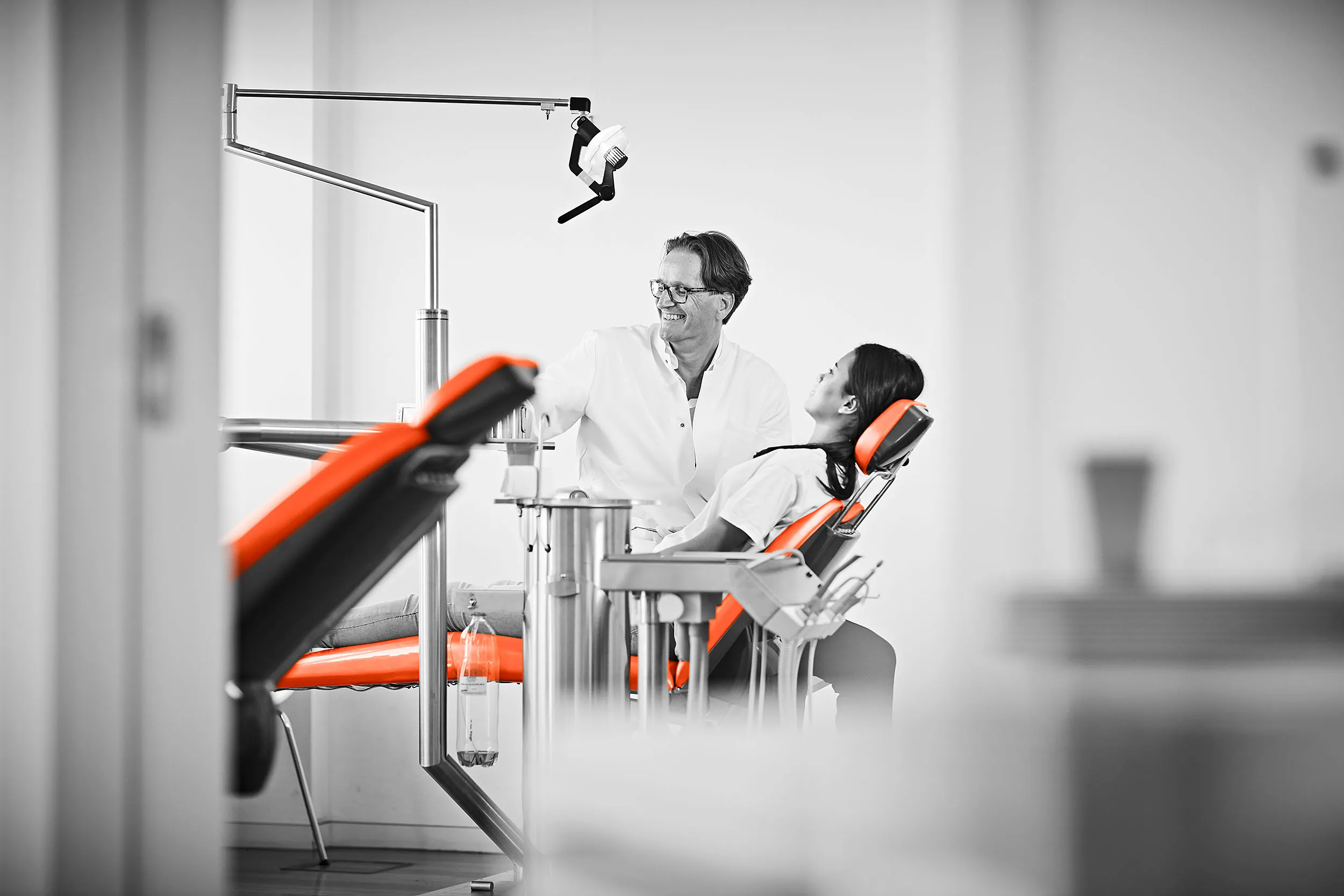 Ritter&Ritter, die Kieferorthopädie mit Herz Eine Frau liegt auf dem Bahandlungsstuhl die von Dr. Ritter lächelnd behandet wird