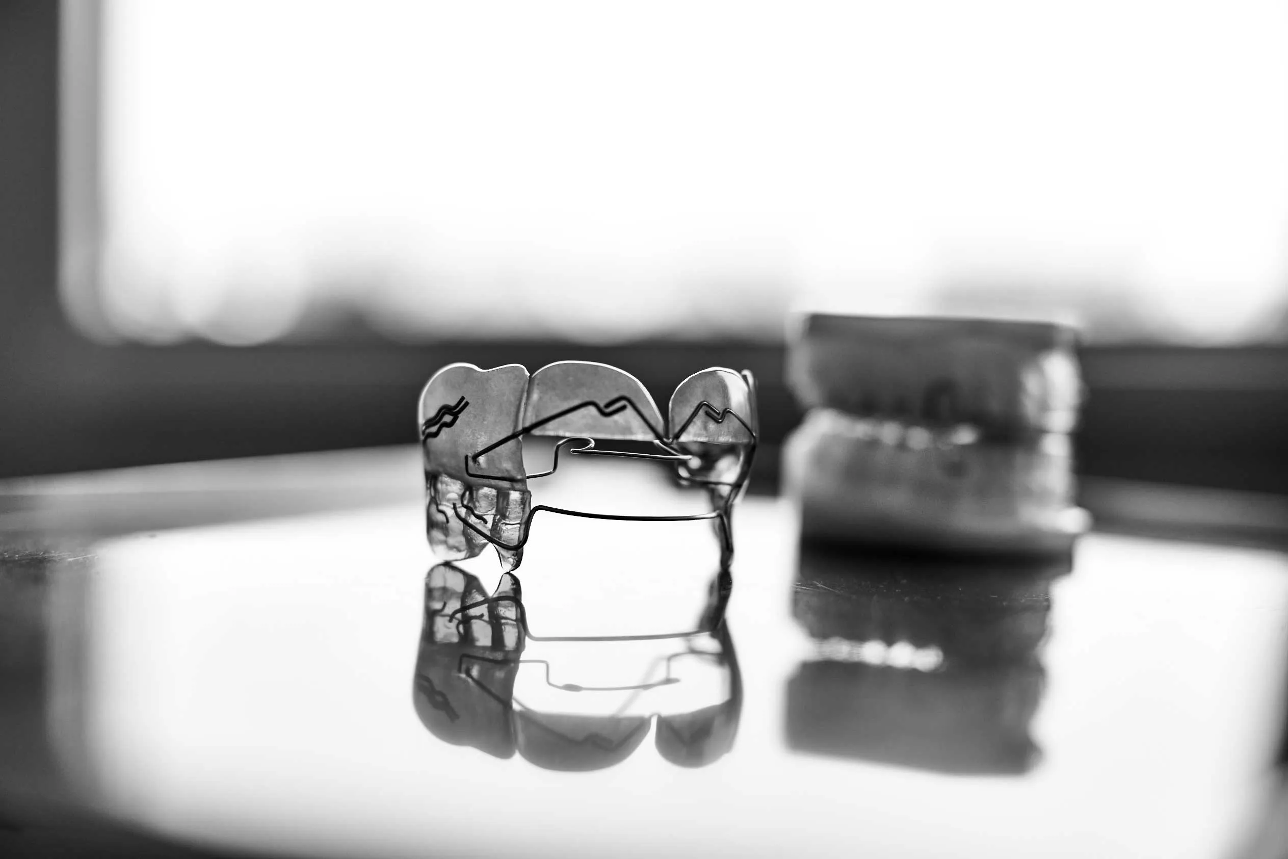 Herausnehmbare Zahnspange liegt auf einem Tisch. Daneben ist ein Gipsmodell des Gebisses.